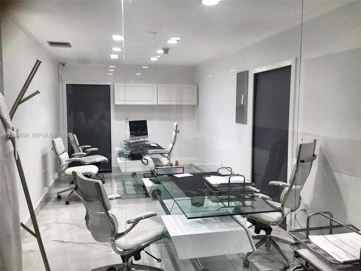 Polished stone flooring, recessed ceiling lighting, wall-mounted upper cabinetry, and glass-partitioned wall enclosure