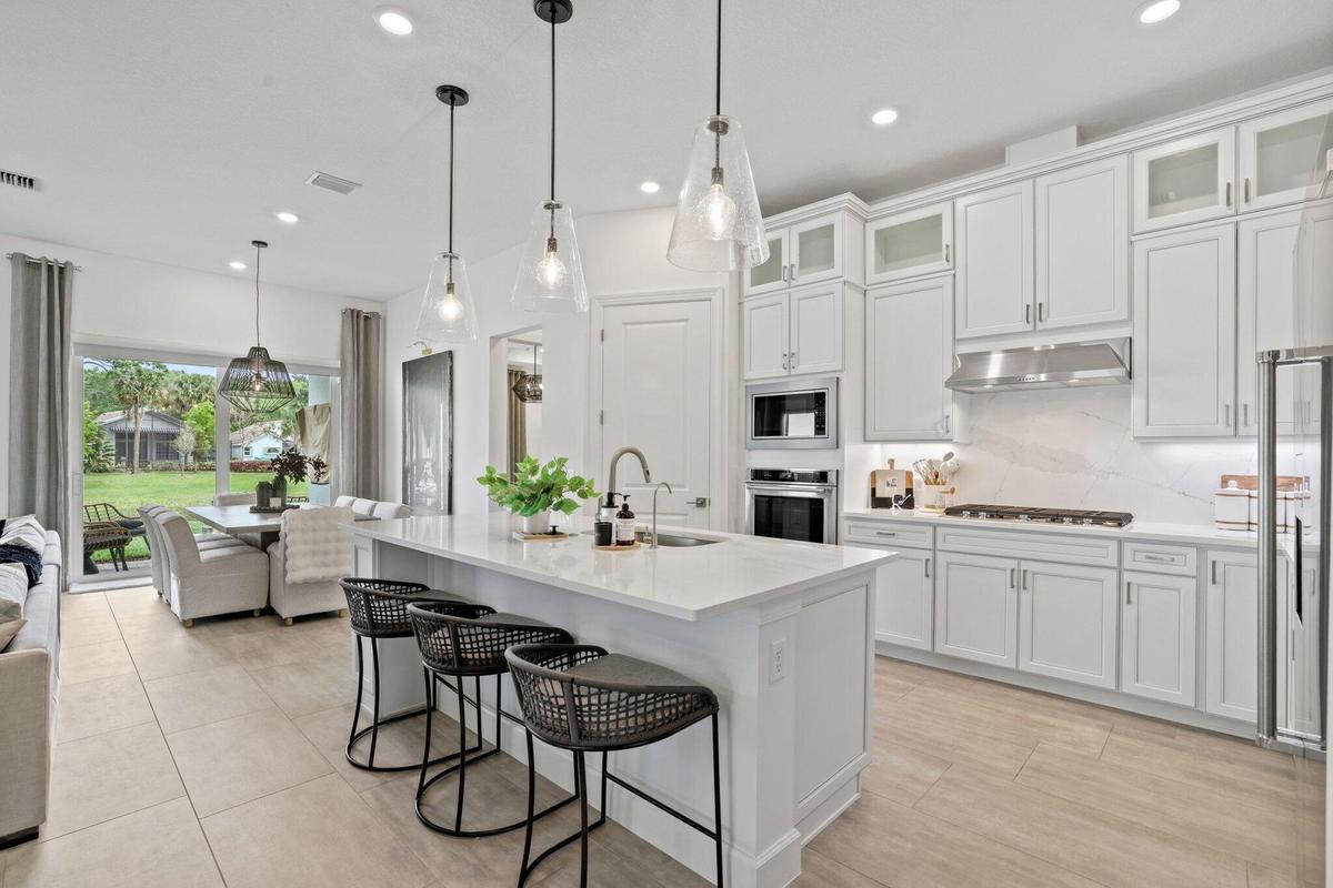 Kitchen featuring white shaker-style cabinetry, a large central island with quartz countertops, stainless steel built-in double wall ovens, a gas cook