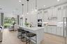 Kitchen featuring white shaker-style cabinetry, a large central island with quartz countertops, stainless steel built-in double wall ovens, a gas cook