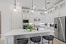 Kitchen featuring white cabinetry with glass-front uppers, solid-surface countertops, a large center island, stainless steel appliances, and three cle