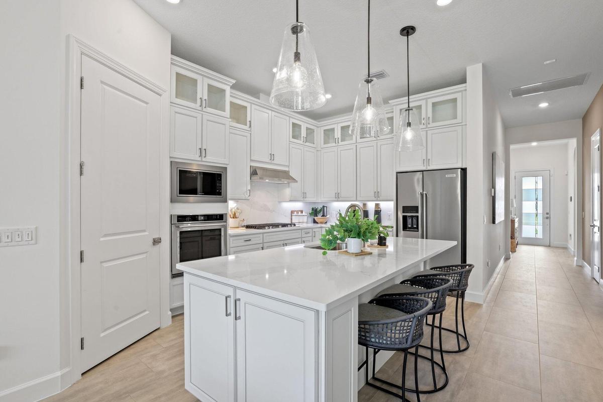Kitchen featuring white shaker-style cabinetry with glass-front uppers, solid surface countertops, a central island, stainless steel appliances, and g