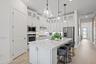 Kitchen featuring white shaker-style cabinetry with glass-front uppers, solid surface countertops, a central island, stainless steel appliances, and g