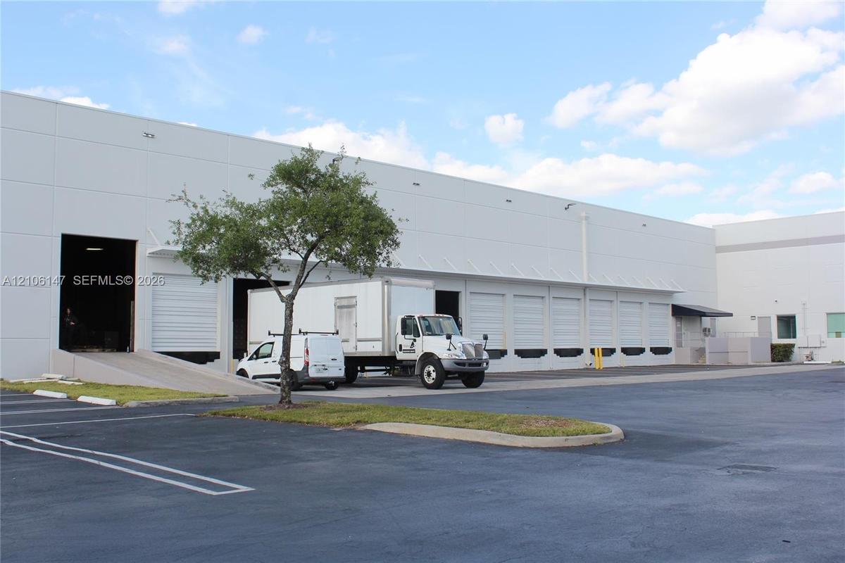 Industrial warehouse facility featuring a concrete tilt-wall exterior, multiple dock-high loading doors, and a dedicated concrete loading ramp