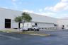 Industrial warehouse facility featuring a concrete tilt-wall exterior, multiple dock-high loading doors, and a dedicated concrete loading ramp