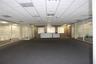 Open floor plan office space featuring integrated glass partitions, recessed lighting, carpeted flooring, and a built-in service counter