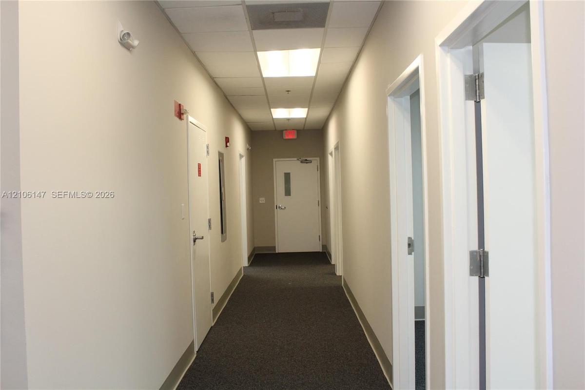 Hallway featuring neutral wall finishes, drop ceiling with integrated recessed lighting, and carpeted flooring