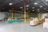 Warehouse interior featuring high-clearance open-span ceilings, steel truss construction, industrial lighting fixtures, concrete flooring, and install