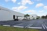 Industrial structure featuring concrete tilt-wall construction, multiple loading docks, and an expansive asphalt parking lot with marked stalls