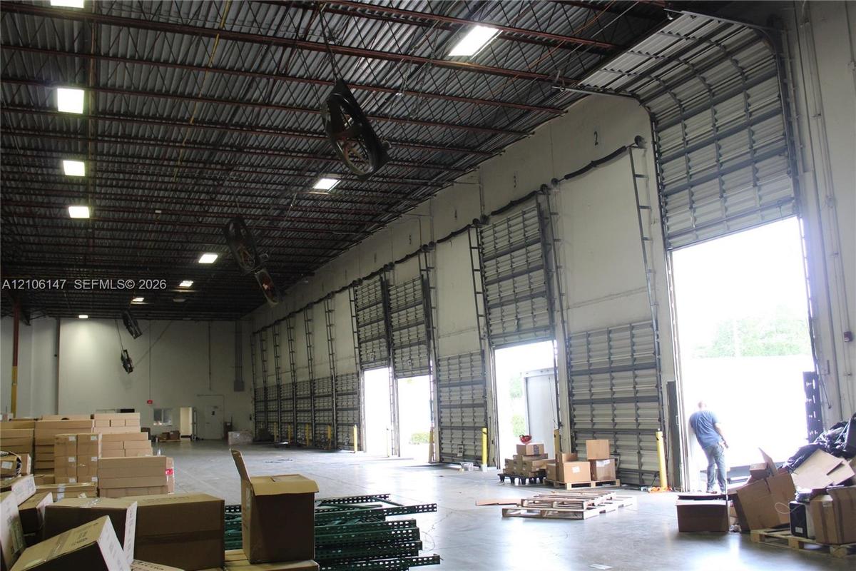 Industrial warehouse interior featuring high-clearance exposed ceilings, multiple grade-level overhead roll-up doors, and polished concrete flooring