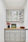 Additional pantry space featuring built-in cabinetry, countertop workspace, and glass-front display cabinets.
