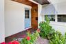 Welcoming covered front entry with attractive architectural details and lush landscaping.