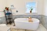 Primary bathroom featuring a freestanding soaking tub and decorative tile accents.