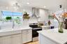 Bright kitchen with farmhouse sink, stainless steel appliances, and attractive cabinetry.