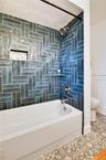 Beautifully tiled bathtub and shower combination with striking blue/green accent tile.