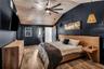 The secluded primary suite blends modern design with inviting comfort, showcasing a striking vaulted plank ceiling, stylish pendant lighting, and an e