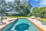 The enormous fully fenced backyard is designed for year-round enjoyment with a gas-heated saltwater sport pool, outdoor kitchen, expansive brick paved