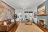 The warm and welcoming Formal Living Room is anchored by a wood-burning brick fireplace accented by a substantial wood mantle and custom painted brick
