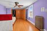 Hardwood-finish flooring, white window trim, and a ceiling fan with integrated lighting