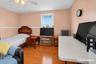 Hardwood-finish flooring, window with natural light, ceiling fan with integrated lighting, wall-mounted radiator, and decorative molding
