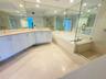 Bathroom featuring a double-sink vanity with white cabinetry and solid surface countertops, a built-in soaking tub, a glass-enclosed shower, expansive