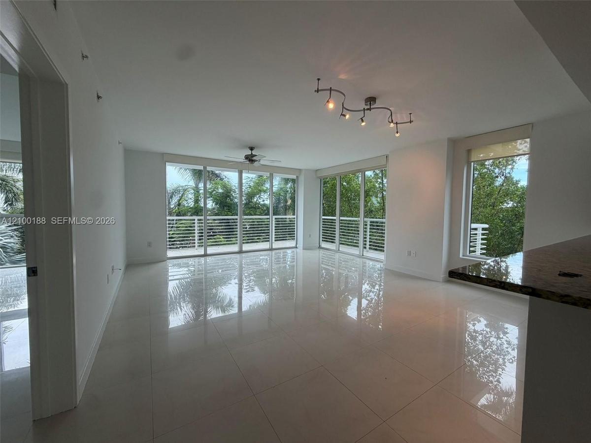 Open-concept interior featuring large-format tile flooring, expansive floor-to-ceiling windows, polished stone kitchen peninsula, contemporary multi-l