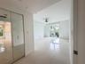 Large-format tile flooring, ceiling-mounted paddle fan, and floor-to-ceiling mirrored closet doors