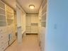 Custom walk-in closet featuring white built-in shelving, floor-to-ceiling cabinetry, integrated hanging rods, and neutral tile flooring
