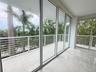 Floor-to-ceiling glass sliding doors, white tiled flooring, and a wrap-around balcony featuring white horizontal railings