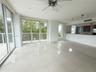 Open-concept interior featuring large-format tile flooring, floor-to-ceiling glass sliding doors, a breakfast bar with stone-finish countertops, and a