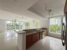 Kitchen featuring natural stone countertops, wood cabinetry, large-format tile flooring, track lighting, and floor-to-ceiling windows