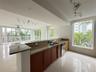 Kitchen featuring stone countertops, wood-finish cabinetry, stainless steel dishwasher, tile flooring, and track lighting