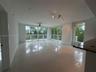 Open-concept interior featuring large-format tile flooring, expansive floor-to-ceiling windows, track lighting, a ceiling fan, and a stone-surface bre