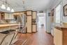Kitchen featuring tile flooring, stainless steel refrigerator, cream-colored cabinetry, wood-finish countertops, and track lighting