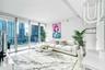 Floor-to-ceiling glass wall, private balcony with glass railing, large-format tile flooring, and contemporary sculptural lighting fixture