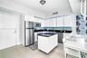 Kitchen featuring white flat-panel cabinetry, dark stone countertops, stainless steel appliances, a mobile center island, and tiled backsplash