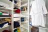 Customized walk-in closet featuring floor-to-ceiling white shelving, integrated adjustable storage cubbies, and dual soft-close drawers