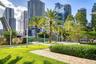 Landscaped outdoor grounds featuring a manicured lawn, palm trees, clipped hedges, and brick paver walkways