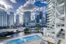 Rectangular outdoor swimming pool with a concrete pool deck, multi-level glass-paneled balconies, and architectural skyscraper exterior