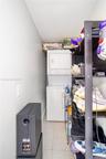 Dedicated laundry area featuring a stacked washer and dryer unit and neutral floor tiling