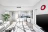 Open-concept kitchen featuring high-gloss cabinetry, stone countertops, stainless steel appliances, and a central peninsula