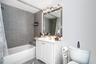 Bathroom featuring a white vanity with built-in cabinetry, a rectangular basin with a single-handle faucet, a framed mirror, a multi-bulb vanity light