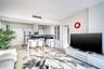 Open-concept kitchen featuring high-gloss white cabinetry, contrasting dark countertops, stainless steel appliances, and a modern sculptural pendant l