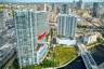 High-rise residential tower featuring a multi-level swimming pool deck, glass balcony railings, floor-to-ceiling windows, and direct urban skyline exp