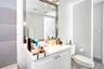 Bathroom vanity featuring a solid-surface countertop, integrated basin, brushed metal faucet, and framed rectangular mirror with integrated lighting