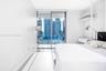 Floor-to-ceiling glass sliding doors, large-format tile flooring, built-in shelving unit with an integrated drawer, and urban skyline backdrop