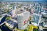 Aerial perspective of high-rise building featuring expansive balcony space, glass exterior cladding, and proximity to urban infrastructure and waterwa