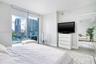 Floor-to-ceiling glass sliding doors, private balcony, large-format tile flooring, and urban skyscraper backdrop
