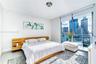 Floor-to-ceiling glass wall, private balcony with metal railing, neutral tile flooring, and integrated wood-finish headboard