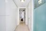 Hallway featuring large-format tile flooring, ceiling-mounted light fixtures, extensive floor-to-ceiling built-in cabinetry, and a walk-in closet with