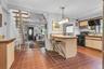 Kitchen featuring terracotta-style tile flooring, a peninsula with an integrated breakfast bar, a gas range, and wood-finish cabinetry